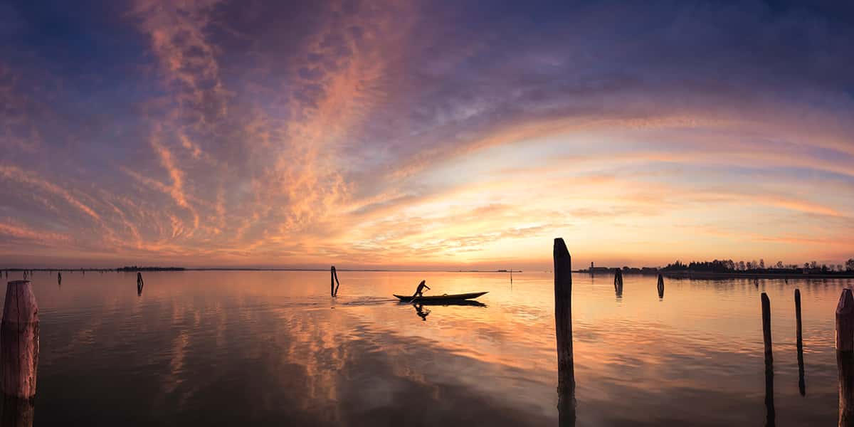 Eine einsame Gondel mit einer Person vor der Insel Burano in Venedig
