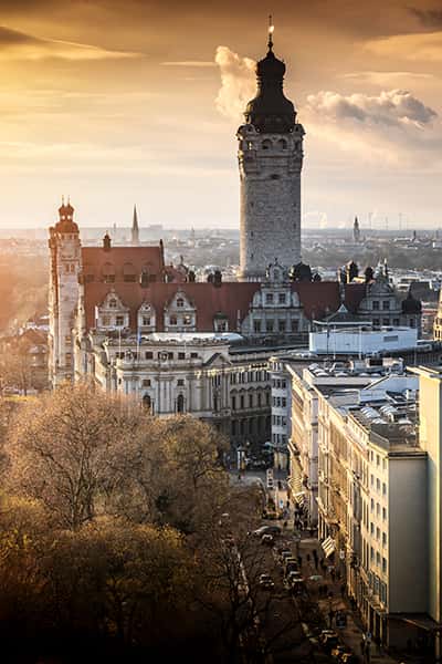 Ein Turm und einige Gebäude in Leipzig bei orangenem Himmel