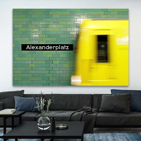  Einfahrende gelbe U-Bahn an der Station Alexanderplatz mit Schriftzug in einem Raummilieu