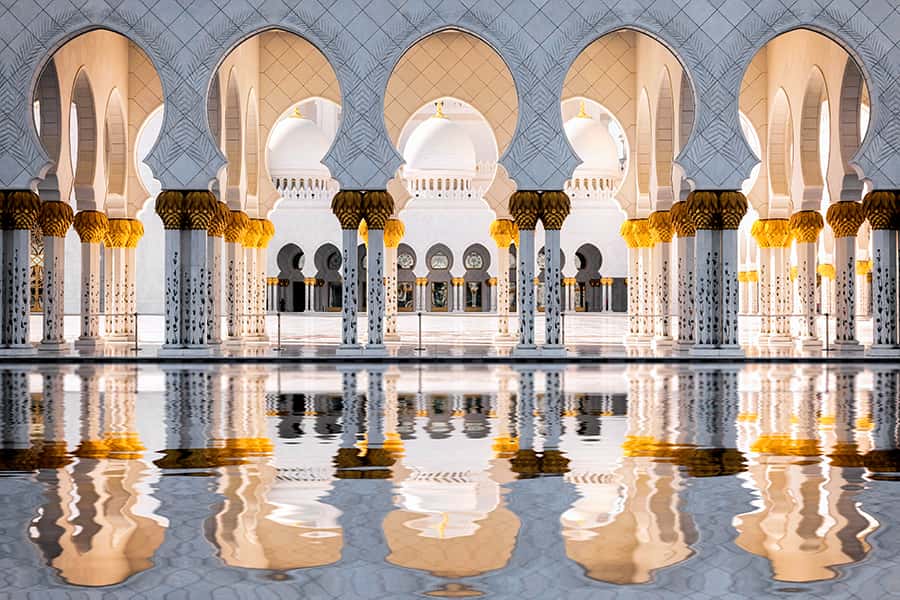 Die Säulen der Scheich Zayid Moschee spiegeln sich im glänzend weißen Boden