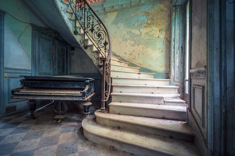 Ein Klavier neben einer Treppe einer verlassenen Villa