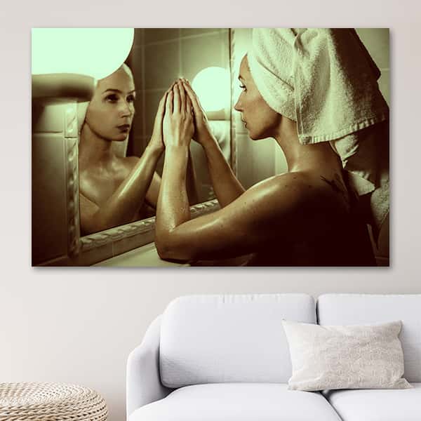 Eine frisch geduschte Frau blickt in den Spiegel in einem Raummilieu