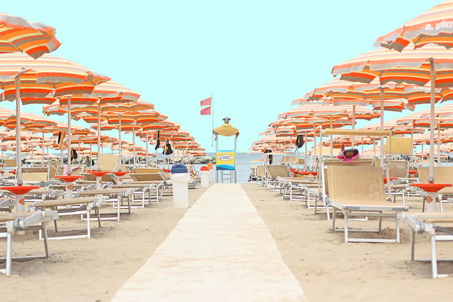 Strandschirme dicht bei einander mit Stühlen am Strand