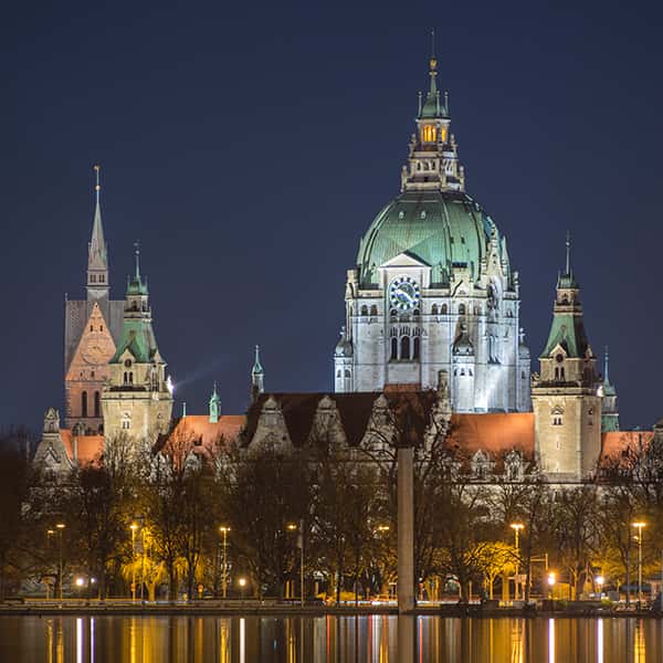 Das Rathaus in Hannover zu Abend und Laternen leuchten am Wasser