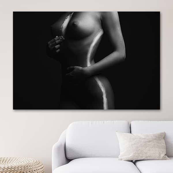 Eine nackte Frau zeichnet sich mit weißer Farbe Striche auf den Körper in einem Raummilieu