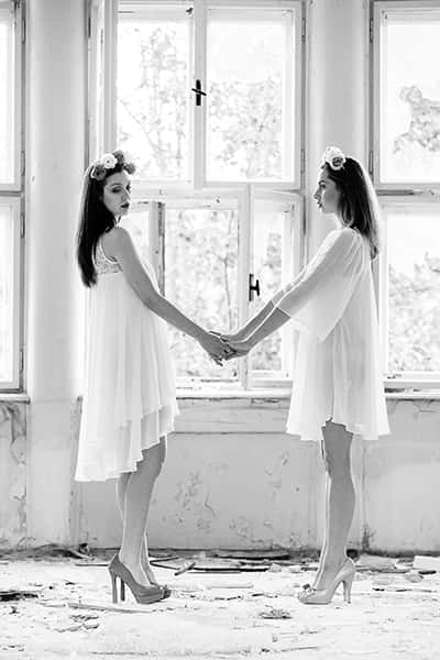 Zwei Mädchen in einem weißen Kleid mit hochhakigen Schuhen halten Händchen