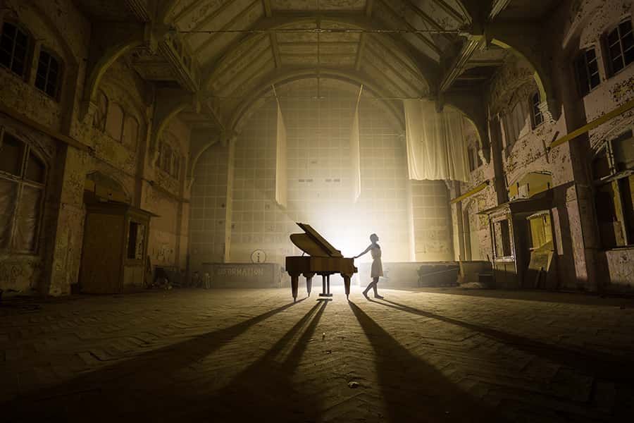 Ein Klavier und ein Pianist in einem großen leicht beleuchteten Raum
