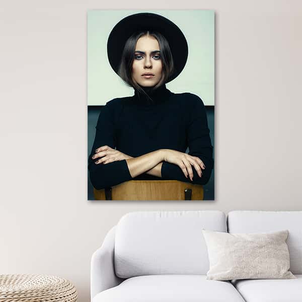 Eine Frau mit Hut und schwarzen Rollkragen Pullover auf einem Stuhl in einem Raummilieu