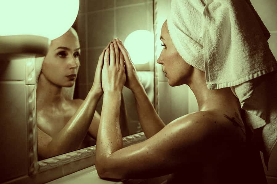 Eine frisch geduschte Frau blickt in den Spiegel