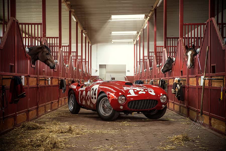 Ein roter Ferrari 375 MM Spider Pinifarina im Gang eines Pferdestalls