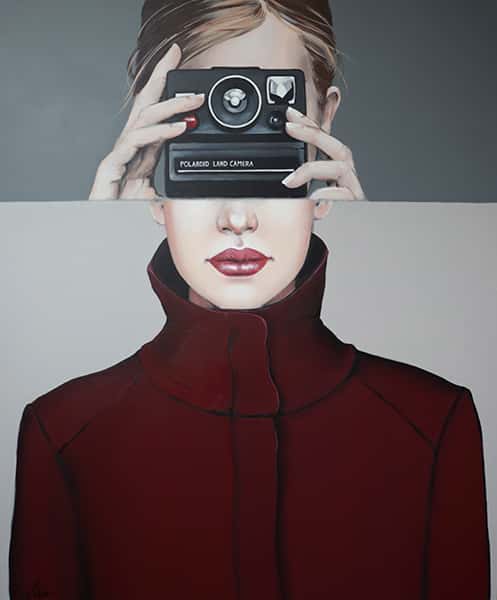 Eine Frau mit einer Kamera vor ihrem Gesicht und einer roten Jacke