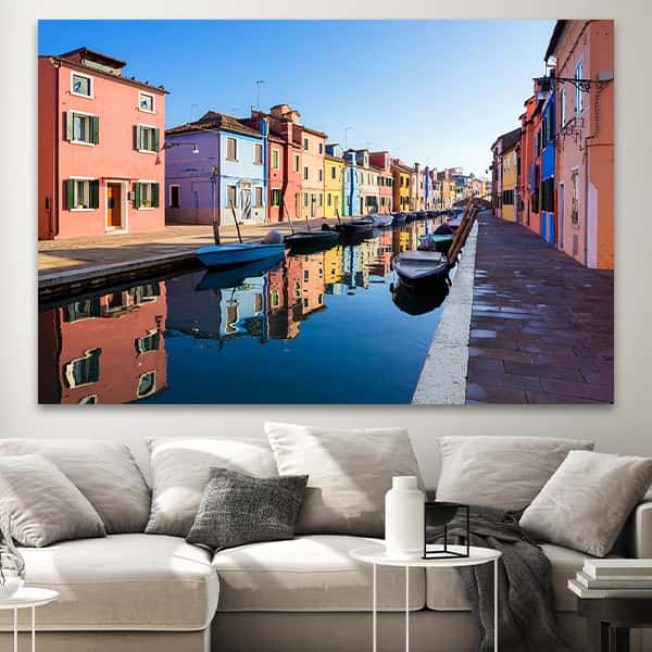 Zwei Reihen bunte Häuschen in Venedig werden getrennt durch eine Wasserstraße in einem Raummilieu