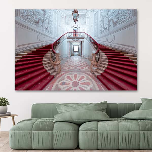 Zwei Treppen mit rotem Teppich führen den Betrachter in die zweite Etage in einem Raummilieu